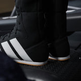 Black Adidas boxing boots with white stripes on a dark background